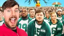 MrBeast stands left in a pink jumpsuit with an excited expression on his face. Behind him is a crowd of people in green hoodies with numbered patches. Behind the crowd is a tree with no leaves and an animatronic girl taller than the crowd. To the right is a small house-like structure in the background.