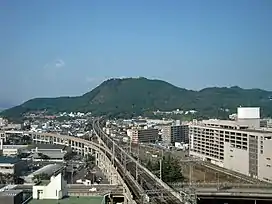 Mt. Shinobu rises from the center of the city of Fukushima. Train tracks can be seen going through a tunnel in the mountain.