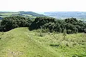 A low green ridge bends away to the right, in the background is a distant shore below the hill