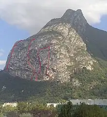 Layout of 4 climbing routes in a vertical wall at the end of a rocky ridge seen from a low angle.