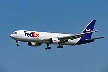 Side quarter view of twin-engine jetliner in flight, with extended gear.