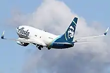A plane painted with the words "Alaska Air Cargo" across it takes off