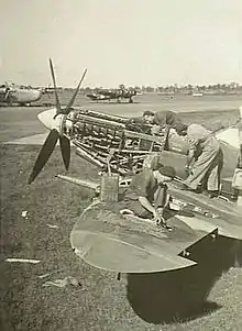 Three men servicing a single-engined military aircraft