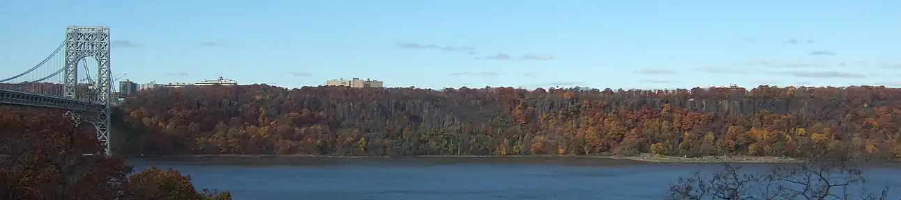 The Palisades, with fall foliage. On the left is the George Washington Bridge. A controversial plan to build a high-rise that would have broken the tree line was proposed, and later modified, by LG Electronics.