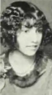 A young Black woman with light skin, hair cut into a curly bob with bangs