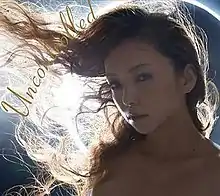 A blue-tinted close-up face shot of a woman, with long hair being windswept to her right. In the background is an extreme close-up of an annular solar eclipse.