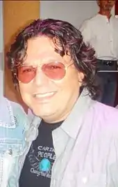A man wearing sunglasses is smiling towards the camera