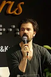 A man (Nathan Larsson) speaking into a microphone.