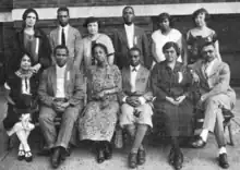 A group of six African-Americans, seven women and five men, posed for a group photo in two rows, six standing behind six seated.