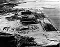 Naval Air Station, Kaneohe Bay, after the Pearl Harbor raid. With burnt hanger, seaplane PBY, the 5 seaplane ramps are visible.