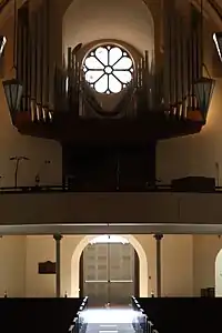 View down length of nave, with front entrance, organ, and rose window at end.