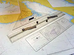 A "Cras navigation plotter" double-protractor, in foreground, named after its inventor Jean Cras.