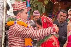Groom tying a dubo garland on his bride's neck, in a Nepalese Khas Hindu wedding.