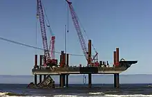 Jackup barges being used to dismantle a ship that was wrecked at sea.