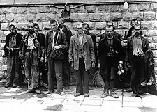 Several men standing in front of a brick wall.