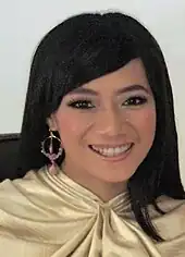 Photo of Nia Dinata in a gold-colored shirt whilst smiling.