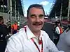 Nigel Mansell in a white T-shirt with a red remembrance poppy smiling at the camera