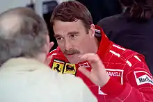 Nigel Mansell in racing outfit talking to another man