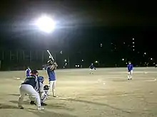 A metal-halide light bank at a softball field