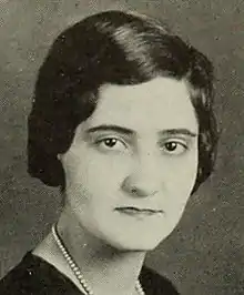 Black and white portrait of a short-haired woman in a dark blouse wearing pearls