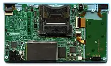 A large and small printed circuit board connected together. A metal chassis and main electronic components dominate opposite ends of the large PCB.