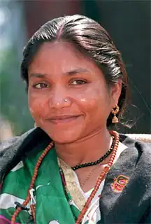 Head and shoulder photograph of woman halfsmiling past camera. She wears a brown necklace and her black hair is pulled back.