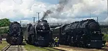 Three steam locomotives on display with one in the middle being operational