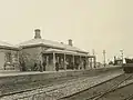 Station building with signal box in background, about 1880