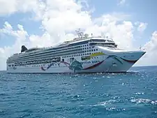 A white ship several stories, seen from off the starboard side of the bow, with "Norwegian Dawn" painted on the side