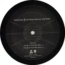 Side one of a black record with a symbol covering the surface and letters mentioning the two versions of the song.