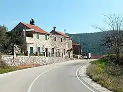 Houses near a road in Nova Sela. A hill is seen in the distance.