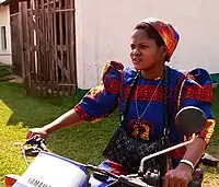 A sister of the Theresienne Sisters of Basankusu wearing a brightly coloured habit, riding a motor-bike, Democratic Republic of Congo, 2013