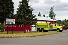 A sign for a fire station, with the building behind it.