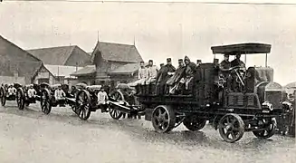 A battery of howitzers on the move.  Note the gun crew members riding on the artillery tractor and seats on the gun carriage.