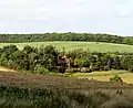The house and gardens of Offley Chase surrounded by fields and rolling hills