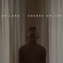 A young boy without a shirt is facing upwards towards the title of the song.