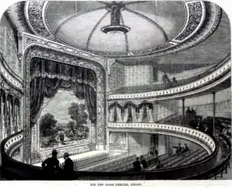 interior of old theatre showing large number of seats and large proscenium arch at front of stage