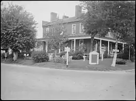 Black and white photo shows a two-story building.