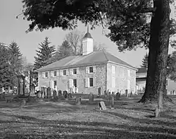 Black and white photograph of a stone church, adjacent to a graveyard