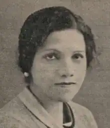 A young South Asian woman with wavy dark hair side-parted and dressed to the nape