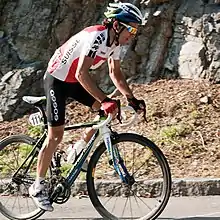 A road racing cyclist wearing a red and white jersey, styled after the Swiss flag.