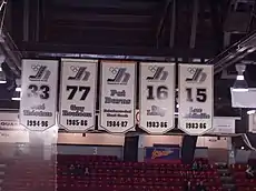 Five banners in white whith black and silver trim hanging vertically from the celing of the arena