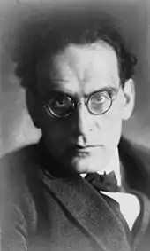 head and shoulder image of man with dark hair and spectacles, glaring towards the camera
