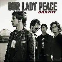 A black-and-white photo of all Our Lady Peace members standing on a beach with a blurred sphere in the background