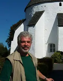 Ove von Spaeth in front of the historical Oesterlars round church on the Danish island Bornholm