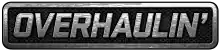 A simple logo spelling the word "Overhaulin'" in block capital letters in silver over what appears to be a car grill or interlaced gray mesh