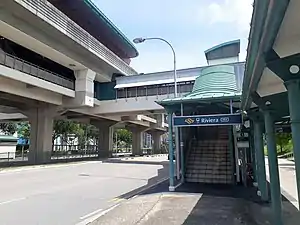 Photograph of station entrance leading to stairs and overhead bridge connecting to the station concourse on the second level.