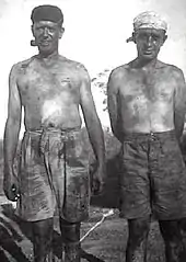 Two men stripped to waist and covered in coal dust, one smoking a pipe