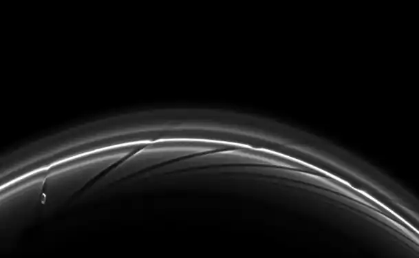 Prometheus near apoapsis carving a dark channel in the F Ring (with older channels to the right). A movie of the process may be viewed at the Cassini Imaging Team website or YouTube.