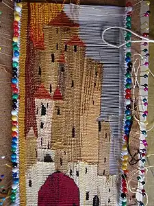 Cotton-and-silk weft-faced tapestry on pins in cork sheet; the complexity of the weft means it has to be woven manually